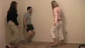 Two chicks are taking turns giving a crazy dude kicks to th